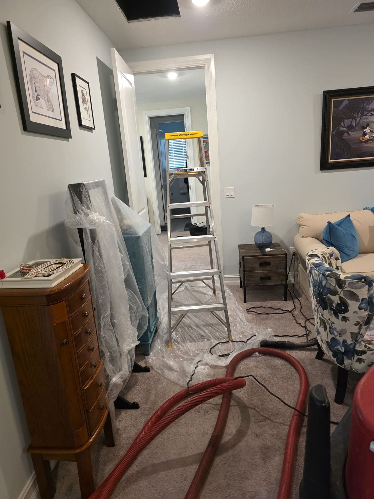 Room set up with ladder and negative-air hose before duct cleaning